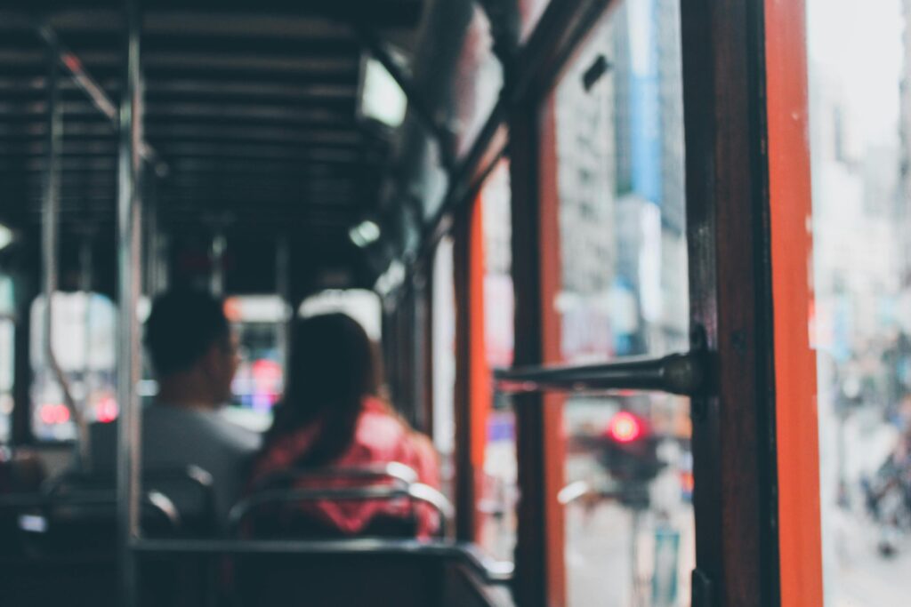 Blurred view inside a Hong Kong double-decker bus with commuters showing city life.