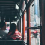 Blurred view inside a Hong Kong double-decker bus with commuters showing city life.