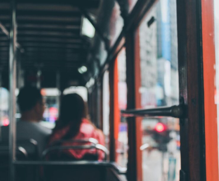 Blurred view inside a Hong Kong double-decker bus with commuters showing city life.