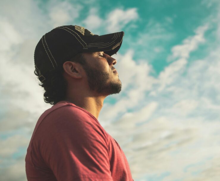 A man enjoys outdoor relaxation and mindfulness beneath a bright, cloudy sky, exuding calm and peace.
