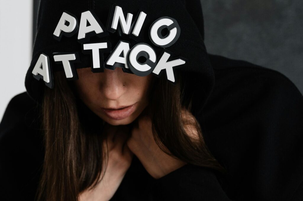 Close-up of a woman in a hoodie with the words 'panic attack', capturing mental health struggles.